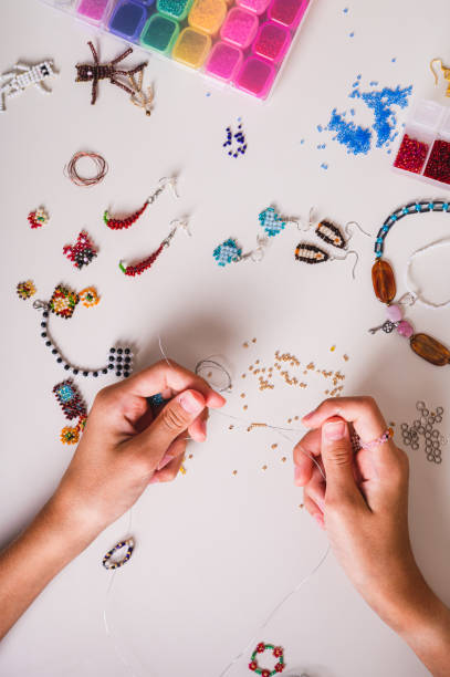 istock A girl's hands string beads onto a wire above a work table with beadwork top view 2167306557