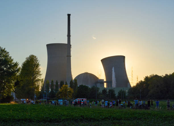 People looking on nuclear power plant cooling tower collapse at sunset in Grafenrheinfeld; Bavaria, Germany - 16.08.2024