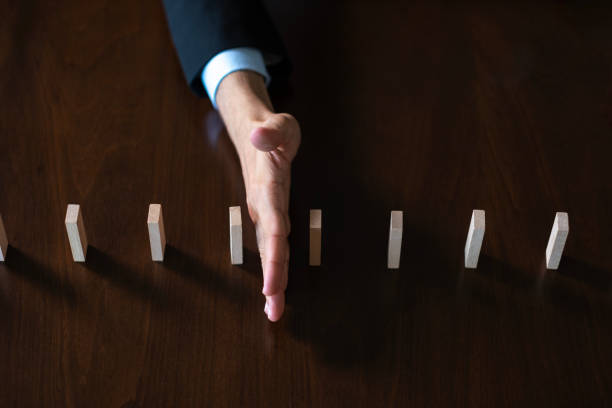 Unknown Businessman in holding with hand falling sequence of wooden blocks