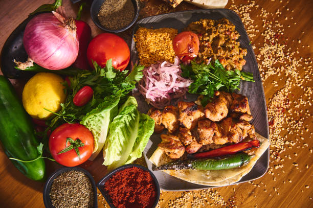 Colorful Mediterranean cuisine with mixed vegetables, grilled chicken, spices, and herbs on a rustic wooden table