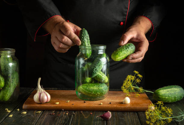 istock Chef hands filling jar with cucumbers before canning with spices on kitchen table. Concept of pickling tasty cucumber 2167312581