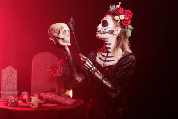 Lady posing with skull in hand, doing Hamlet scene during Dia de los Muertos, preserving cultural traditions. Woman wearing la Catrina costume to celebrate Mexican culture during theatre play
