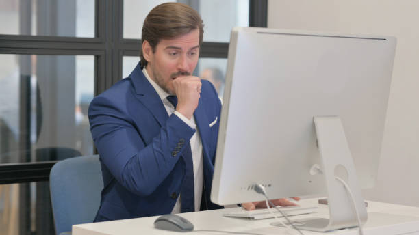 istock Coughing Young Businessman Working on Desktop 2167314065