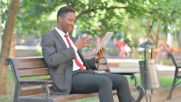 istock African Businessman Doing Video Chat on Tablet while Sitting Outdoor 2167316408