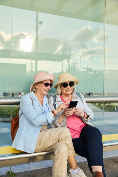 istock Two senior women tourists using a smartphone app for navigation while sitting at the bus stop 2167316813
