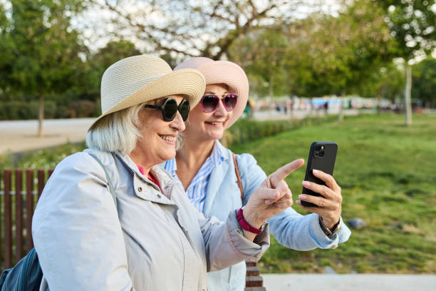 istock Two senior women tourists using smartphone app in city park 2167316921