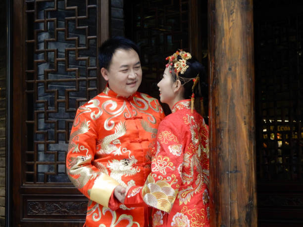 Chengdu, China - November 4, 2016: A couple in traditional red wedding gowns stands outside a building in Chengdu.