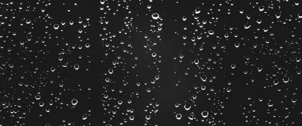 istock Atmospheric minimal grayscale backdrop with rain droplets on glass. Wet window with rainy drops and dirt spots closeup. Blurry minimalist monochrome background of dirty window glass with raindrops. 2167322840