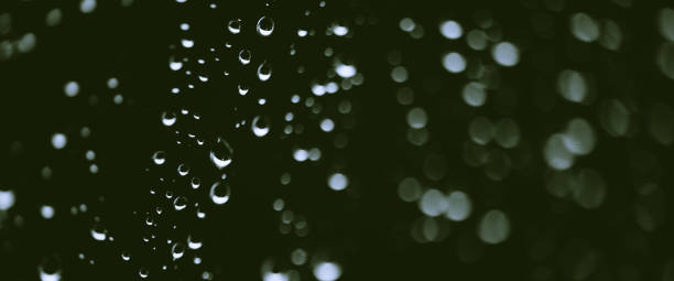 istock Atmospheric minimal monochrome backdrop with rain droplets on glass. Wet window with rainy drops and dirt spots closeup. Blurry minimalist background of dirty window glass with raindrops close up. 2167322843