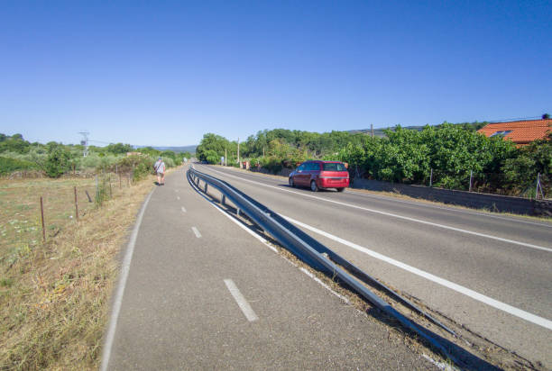 Segregated cycle lane running parallel to a local road. Pedestrian walking