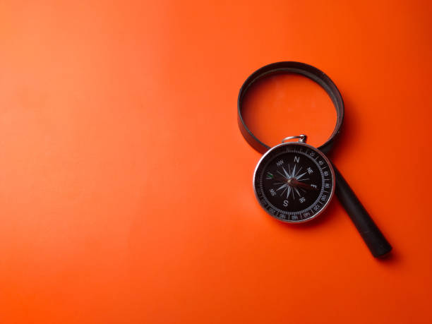 istock Top view compass and magnifying glass on a orange background 2167335808