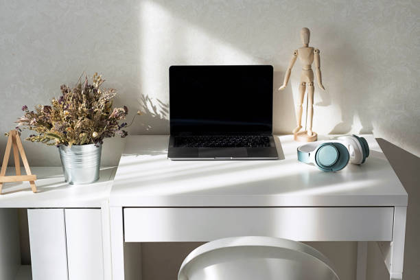 istock Minimalist workspace with laptop, headphones and decor on white desk. 2167336258