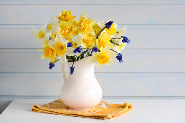 istock garden daffodils and hyacinths in a white jug on the table. a light composition that conveys the feeling of springtime and the beginning of the summer garden season. copy space. 2167336357