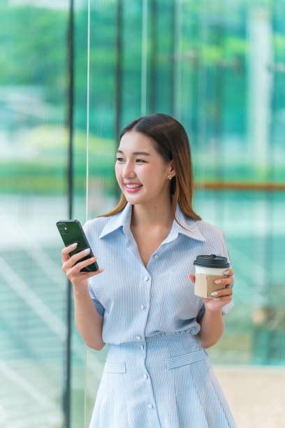 istock Young Woman Using Phone While Having A Cup of Coffee, Looking Away Contented 2167343907