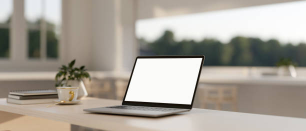 istock A laptop computer with a white-screen mockup on a table in a minimalist white room. 2167344289