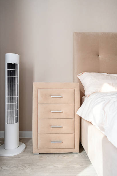 istock White tower fan next to bedside table in light modern bedroom. 2167345578