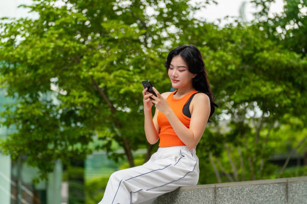 istock Young Woman Sitting In a Park Using Phone Relaxingly 2167346872