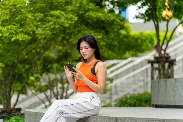 istock Young Woman Sitting In a Park Using Phone Relaxingly 2167346899