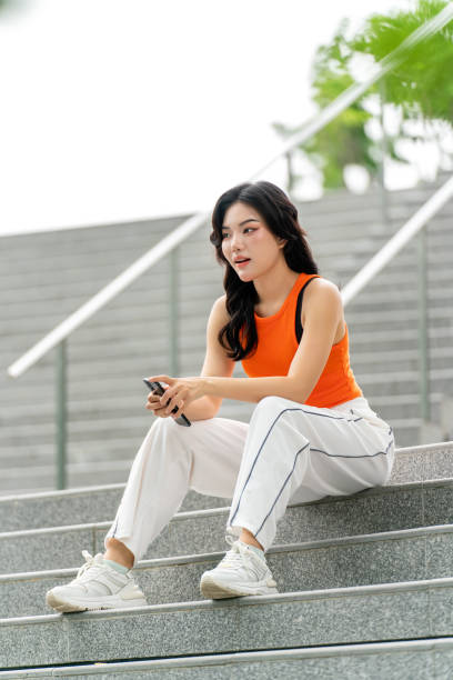 istock Young Woman Using Phone in Park Looking Away Contented 2167346920