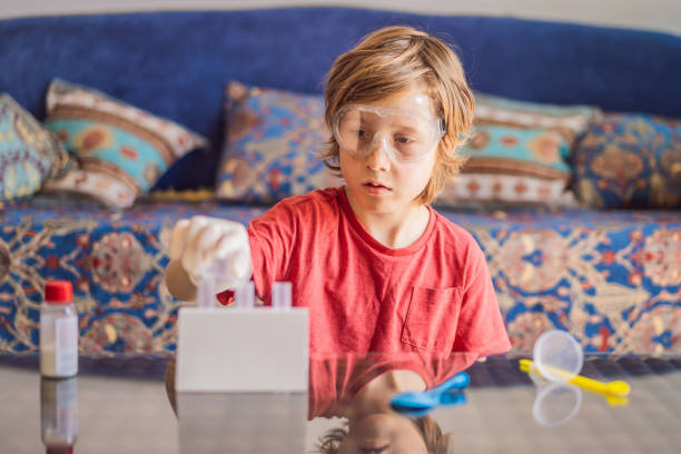 istock Kid boy doing chemical experiment at home. Child with protective glasses study using pipette dropping liquid to test tube, caucasian, biochemistry. chemistry class. home school concept 2167347202