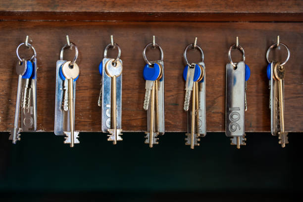 A row of old-fashioned metal keys with number tags hangs neatly on hooks against a dark wooden backdrop, evoking a nostalgic boutique lodging ambiance.