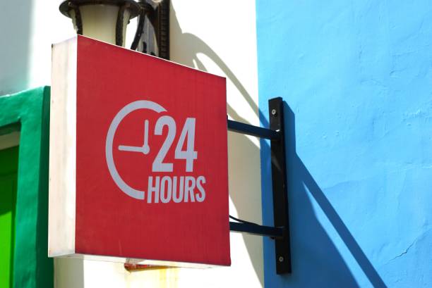 24 hours signboard hanging on the wall on a sunny day, always open business