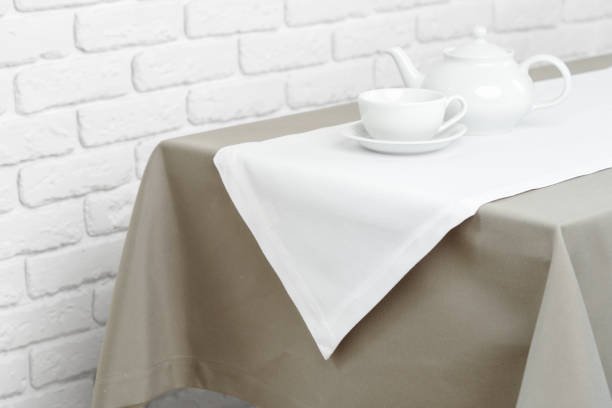 istock Beige Tablecloth on White Brick Wall With Teacups and Teapot 2167350046