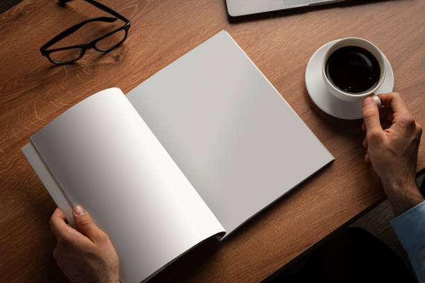 Man Reading Page of Magazine While Holding Coffee Cup