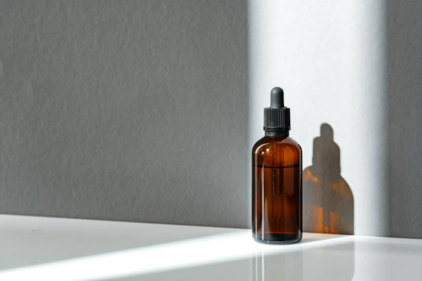 istock Amber Glass Dropper Bottle With Sunlight Shadow on White Surface 2167351950