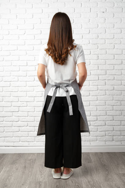 istock Back view Woman Wearing Apron in Front of a White Brick Wall 2167353207