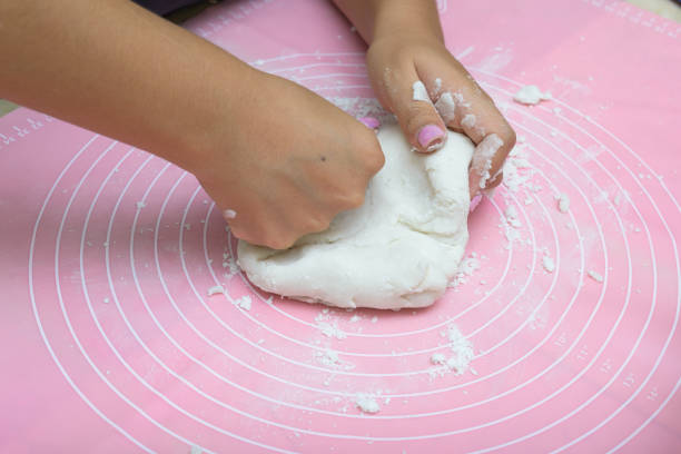 istock Female hands preparing sugar paste on a pink cake mat. 2167355390