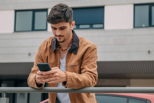 istock Casual young man looking at mobile phone on street 2167355596