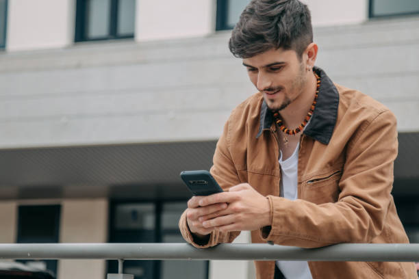 istock Casual young man looking at mobile phone on street 2167355621