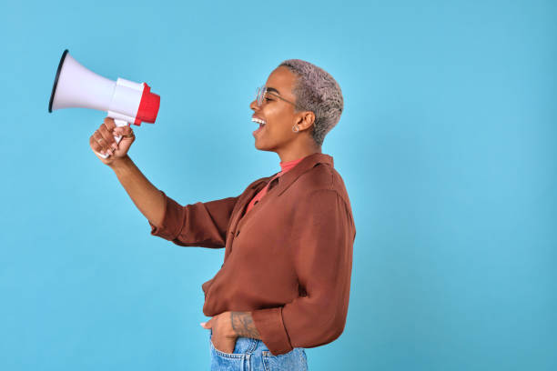istock Young adult enthusiastically speaks into a megaphone against a blue backdrop 2167358961