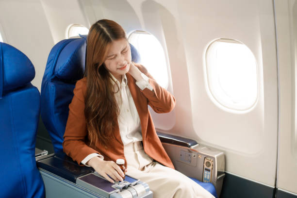 istock A businesswoman travels abroad on a plane, using her computer during the flight. She experiences jet lag, suffering from headaches, neck pain, and stomach ache due to the long journey. 2167359284