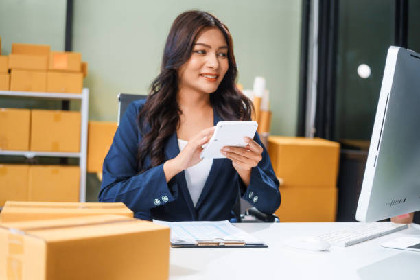 istock A young Asian businesswoman sits at her table, watching the computer screen.She analyzes, plans, and sells products online from home, smiling as she replies to comments and takes orders successfully. 2167360375