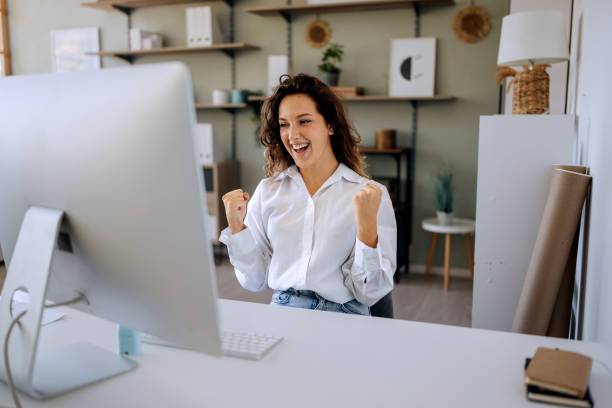 istock Smiling beautiful young businesswoman celebrating success while using desktop PC at the office 2167360615