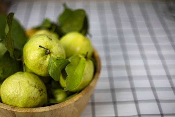 Green guava in the bamboo basket on the table.