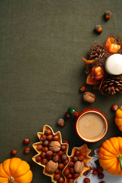 istock Cozy autumn fall background with coffee cup, candle, decorations, pumpkins on green cloth. Top view, vertical, flat lay. 2167361253