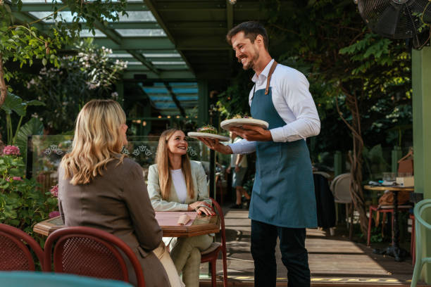 istock Waiter standing with two plates next to a table in a cafe 2167363230