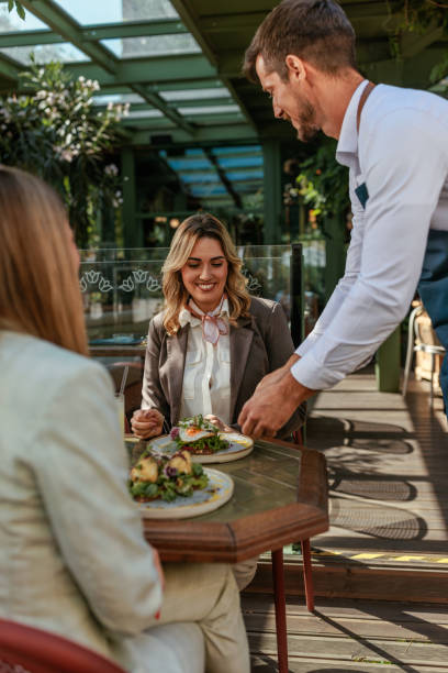 istock Waiter standing by two women at a cafe. 2167363240