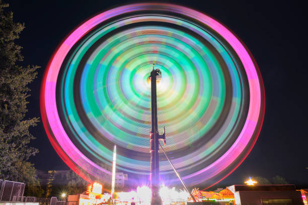 Fair during a summer sunset with illuminated fairground attractions in various colors in the park in Zwolle, Netherlands, during the summer fair. Long exposure photo showing the motion of the fair ride.