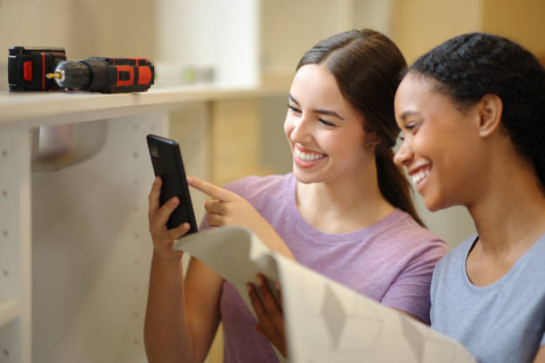istock Happy roommates comparing online manual installing furniture 2167367830