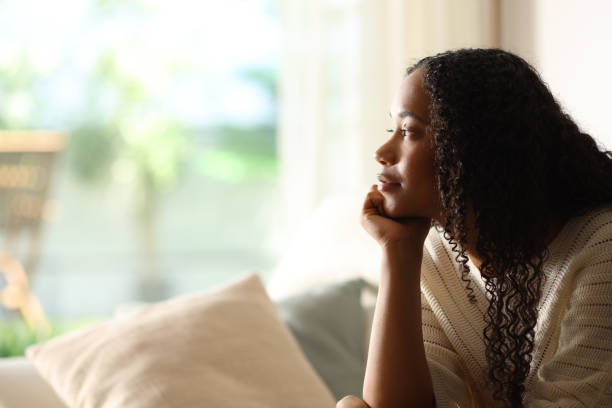 istock Black woman contemplating through a window on a couch 2167367927