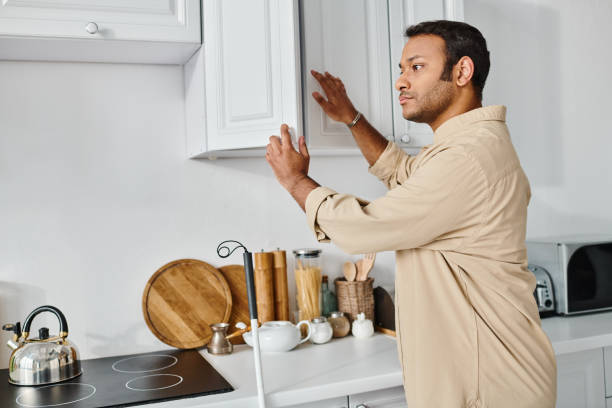 Handsome young man with vision impairment explores his modern kitchen in the morning light