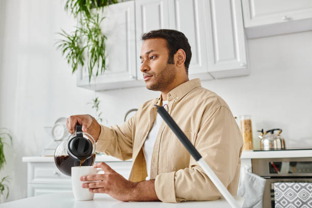 Young man with vision impairment pours coffee in a bright kitchen during the morning