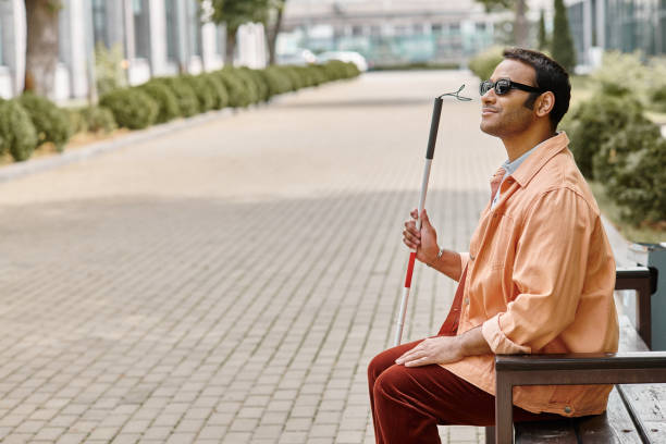 Handsome young man with vision impairment enjoying a sunny day in a tranquil park setting