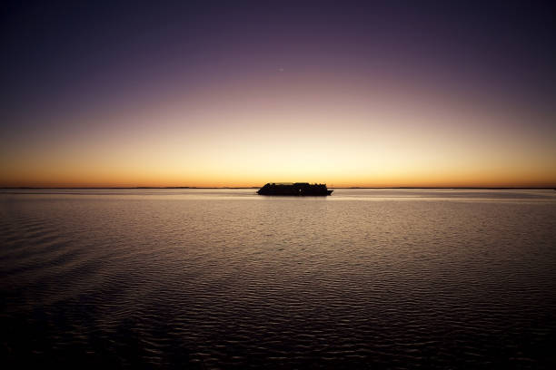 Cargo ship navigating the serene Baltic Sea at twilight, with a breathtaking sky displaying soft hues of orange and purple, reflecting tranquility.High quality photo