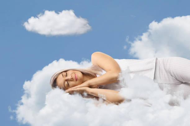 istock Young woman in pajamas sleeping on clouds 2167371469