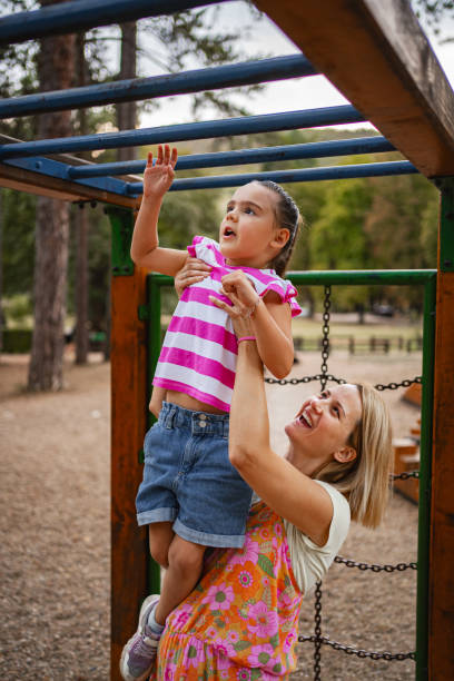 istock Mother assisting twin daughters at a playground during afternoon playtime 2167371601